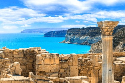 Ancient ruins above a turquoise Mediterranean bay.