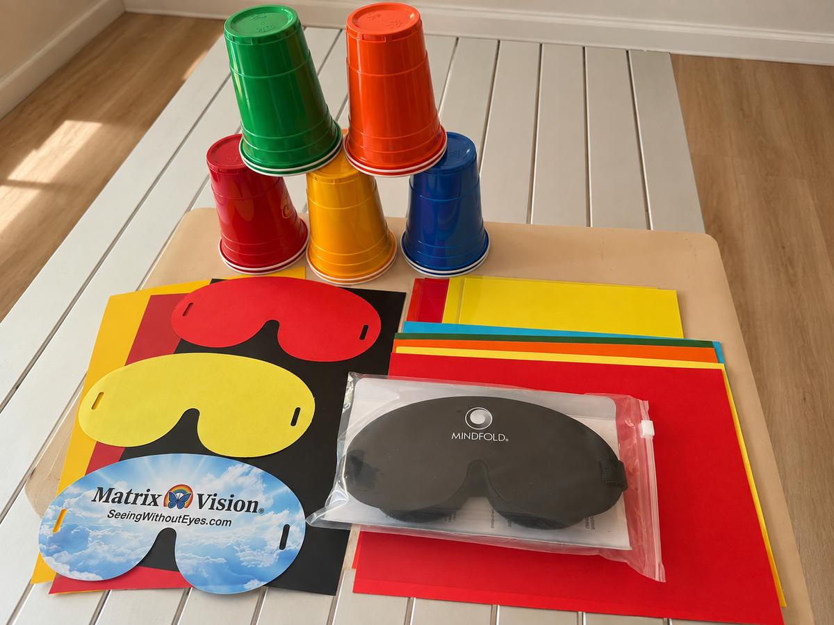 The Training Pack laid out: ten coloured cups, coloured sheets, the red and yellow masks and a blackout mask.